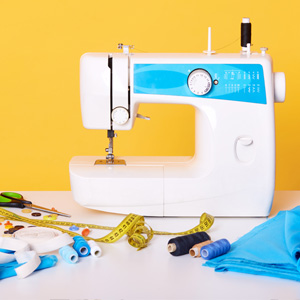 A yellow wall with a blue and white sewing machine in front of it. 