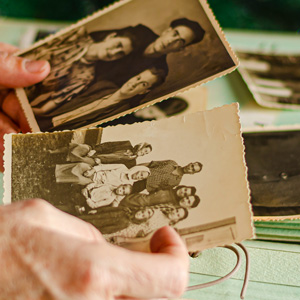 A pair of hands holding two sepia colored family photos
