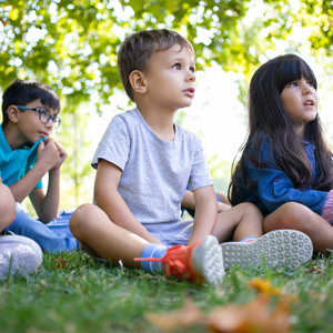 Three children sitting in grass, looking off screen