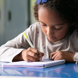 Young child concentrating on writing in a notebook