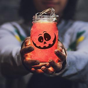 Teen holding out a jar decorated with a jack-o-lantern face and filled with LED lights