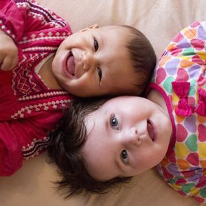 Two babies lying with their heads next to each other