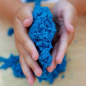 A child's hands playing with blue kinetic sand