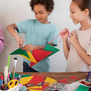 Kids collaborating on art project with supplies in the foreground