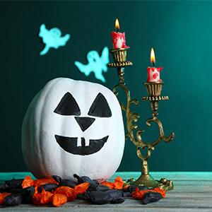 Pumpkin painted like a skull, sitting next to a candelabra