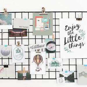 A collection of photos, inspirational sayings, and postcards clipped to a wire grid