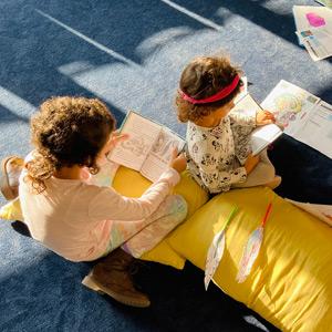 Two young readers follow along with an audiobook