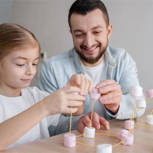 Parent and child building a bridge from marshmallows and noodles