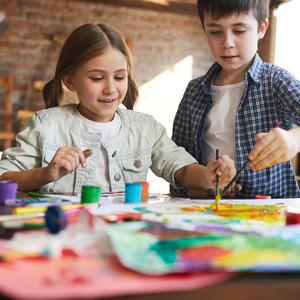 Young siblings smiling while painting