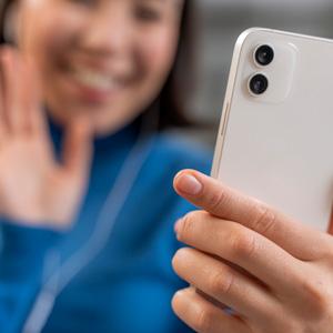 Smiling woman waving at iPhone she's holding