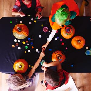 Kids in costumes painting pumpkins