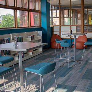 New teen space with tables, comfy chairs, and shelves