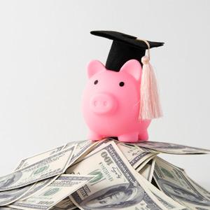 Piggy bank wearing a mortar board atop a pile of money