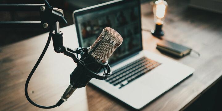 A brown wooden table with a microphone and computer in focus.